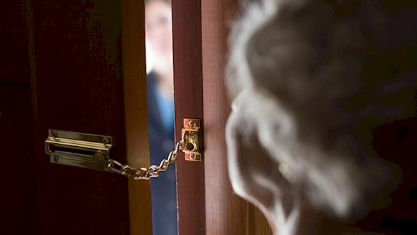 Woman Looking through a Partially Open Door with a Chain Lock